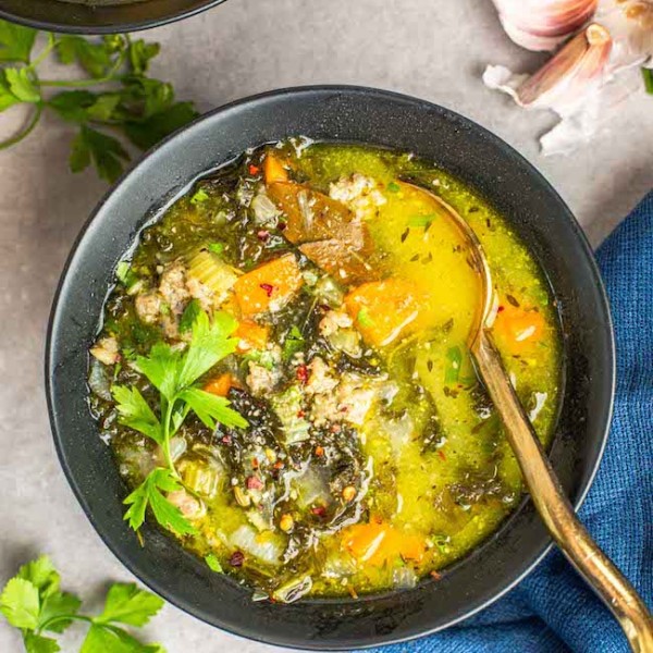 sausage kale soup in a bowl with a gold spoon