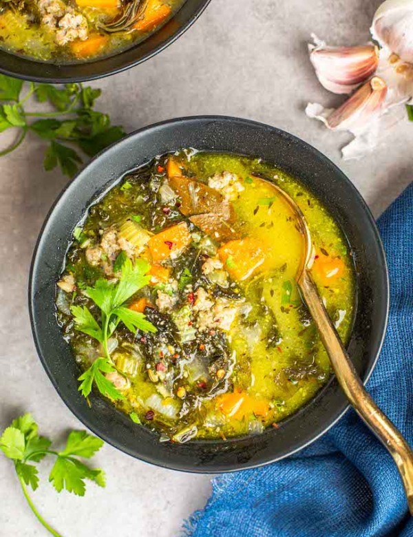 sausage kale soup in a bowl with a gold spoon