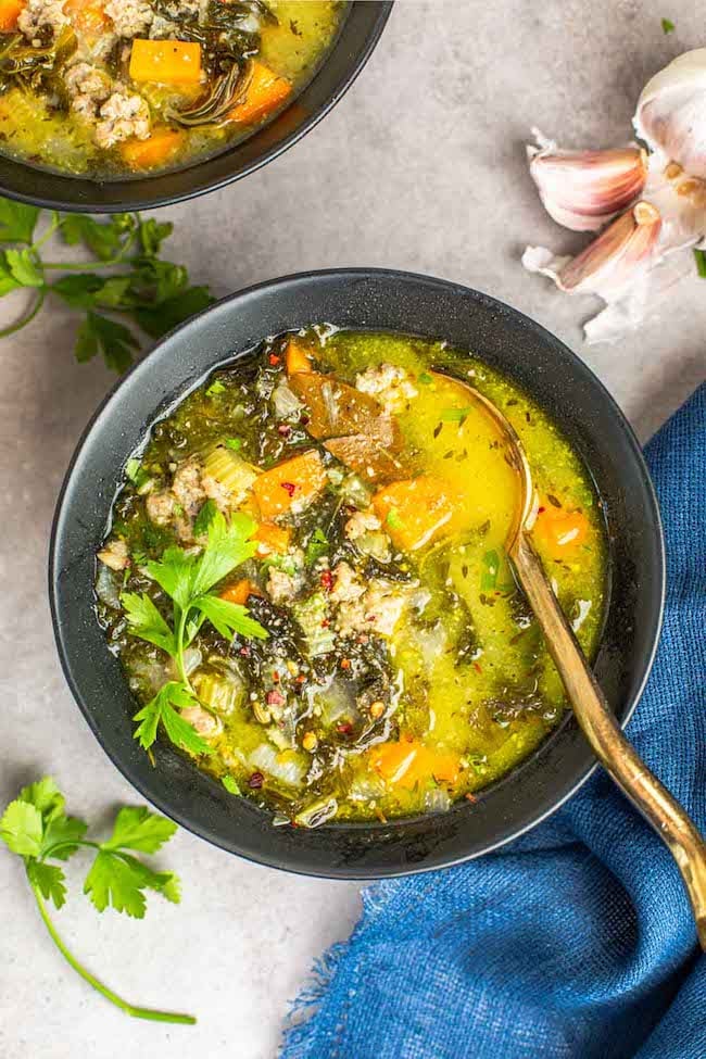 sausage kale soup in a bowl with a gold spoon