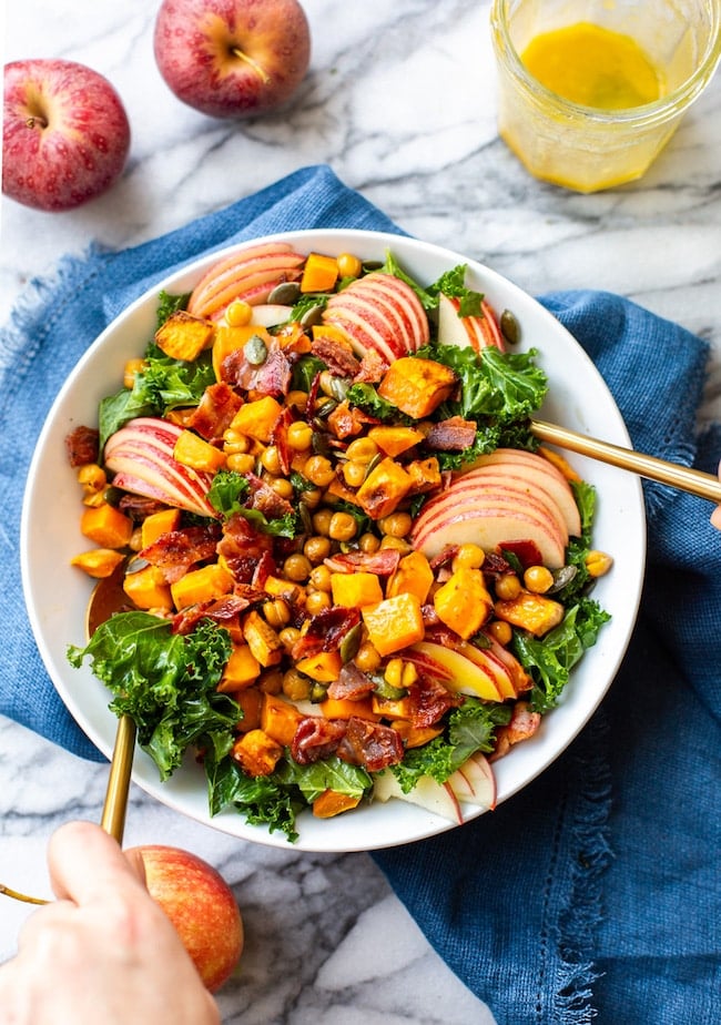 Roasted Sweet Potato & Chickpea Kale Apple Salad with Bacon in a bowl getting mixed together