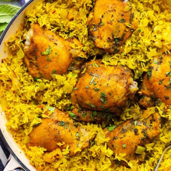 Herby Golden Baked Chicken and Rice in a casserole dish topped with topped herbs