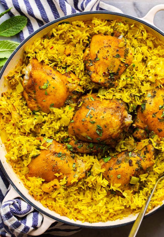 Herby Golden Baked Chicken and Rice in a casserole dish topped with topped herbs