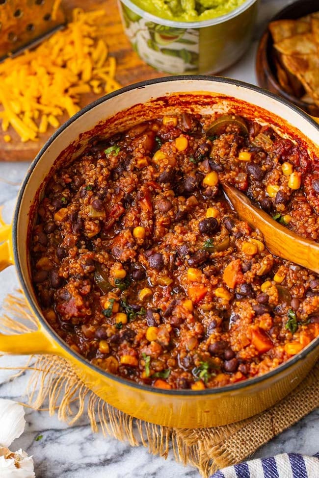 Quinoa Veggie Chili in a big cooking pot with a wooden spoon 