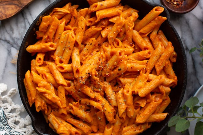 Velvety Garlic & Roasted Red Pepper Pasta in a cast iron skillet topped with oregano 