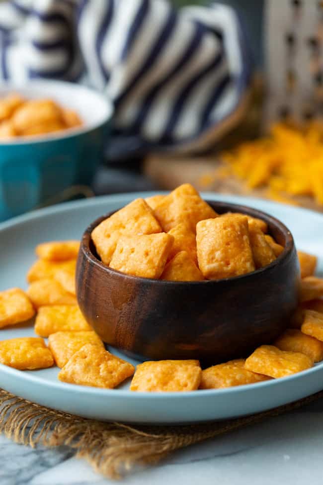 Cheesy Gluten Free Crackers in a small wooden bowl on a blue plate