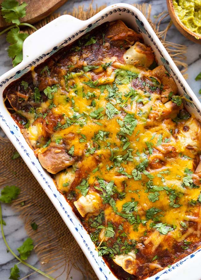 gluten free enchiladas in a casserole dish topped with cheese and cilantro