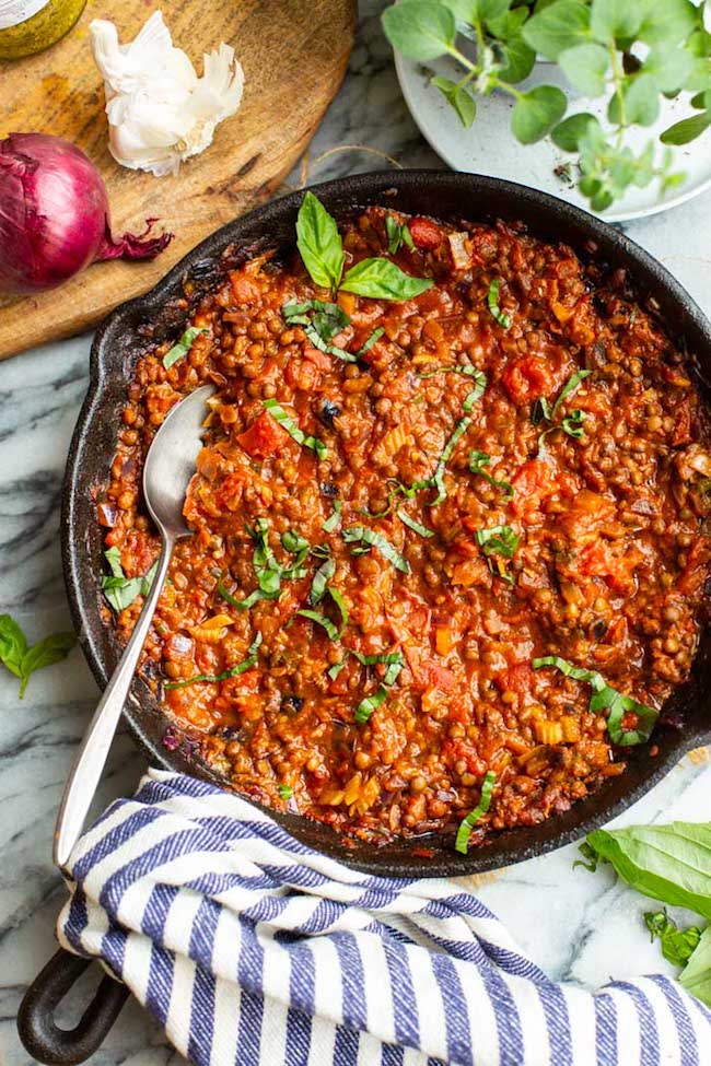 Lentil Bolognese in a cast iron skillet topped with basil