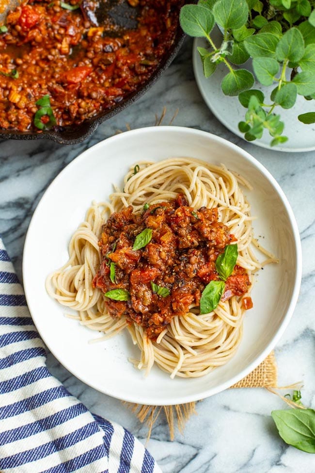 spaghetti topped with Lentil Bolognese in a cast iron skillet topped with basil