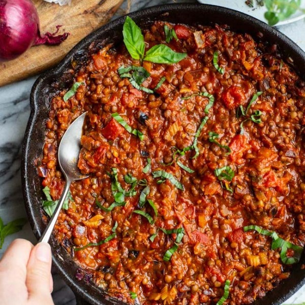 A hand scooping out a spoonful of Vegetarian Lentil Bolognese