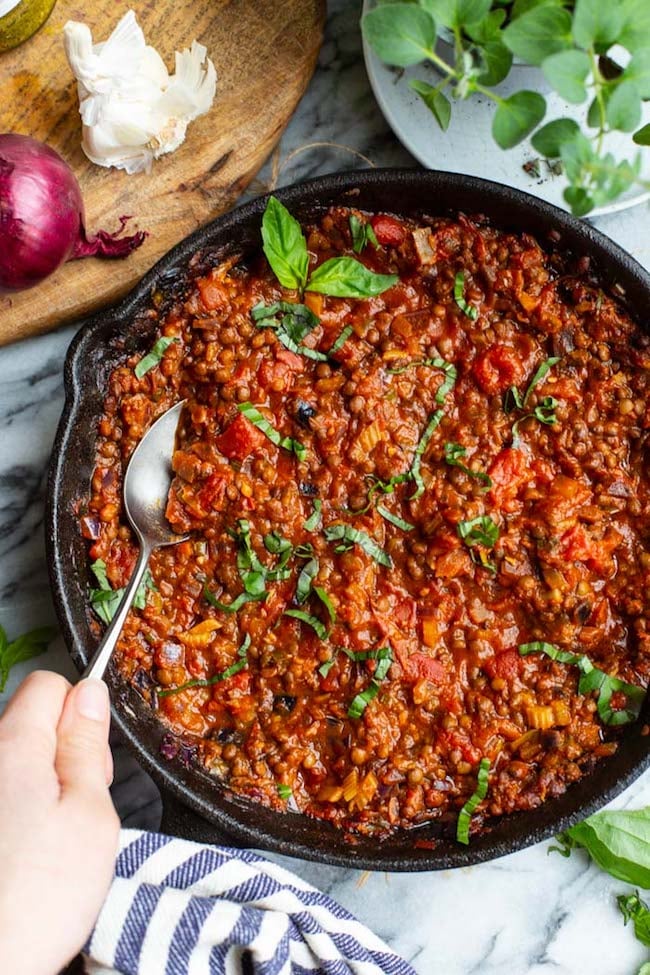 A hand scooping out a spoonful of Vegetarian Lentil Bolognese