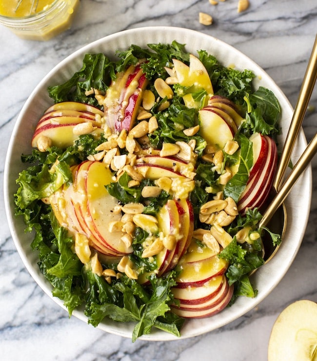 kale salad topped with apples and peanuts