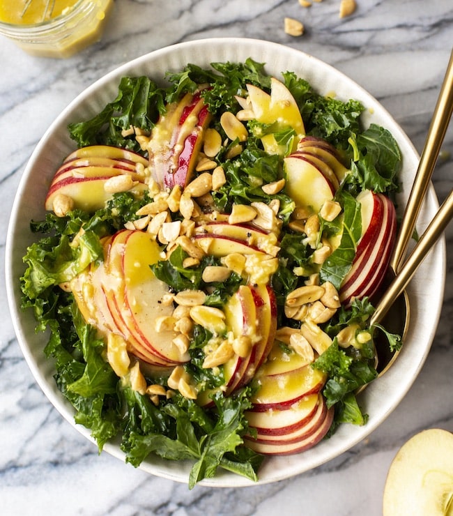 kale salad topped with apples and peanuts 