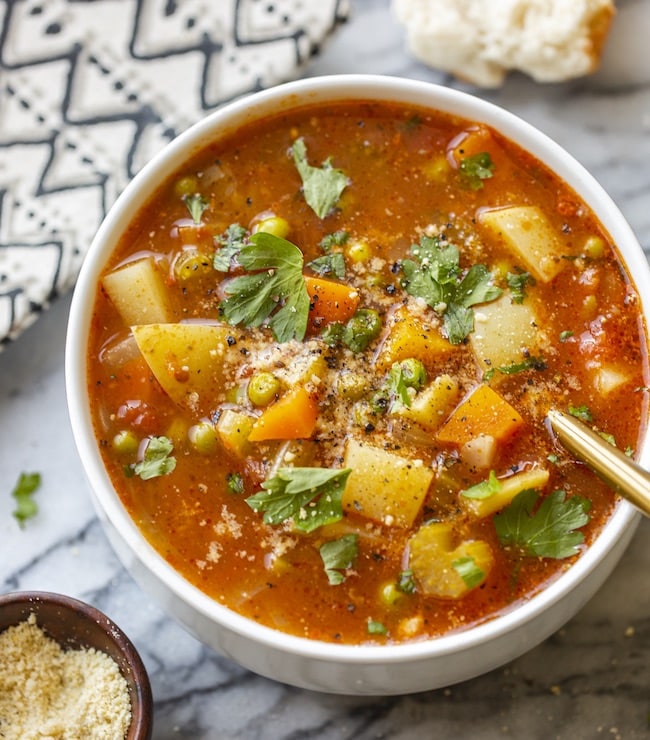 vegetable soup in a white bowl topped with parsley