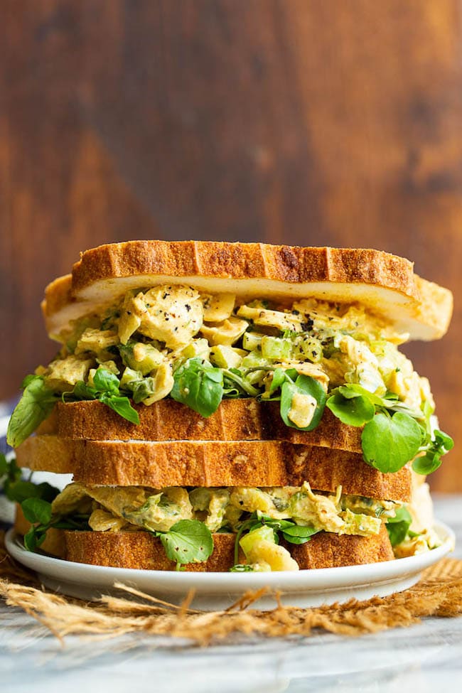 one Coronation Chicken sandwich stacked on top of another on a small plate