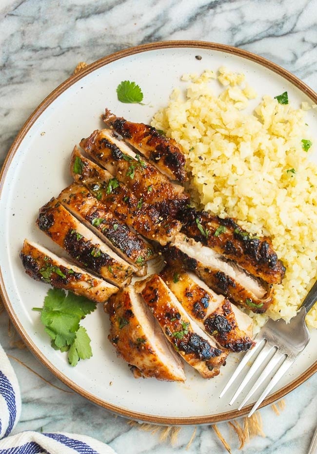 Ping Gai Chicken sliced on a plate with cauliflower rice