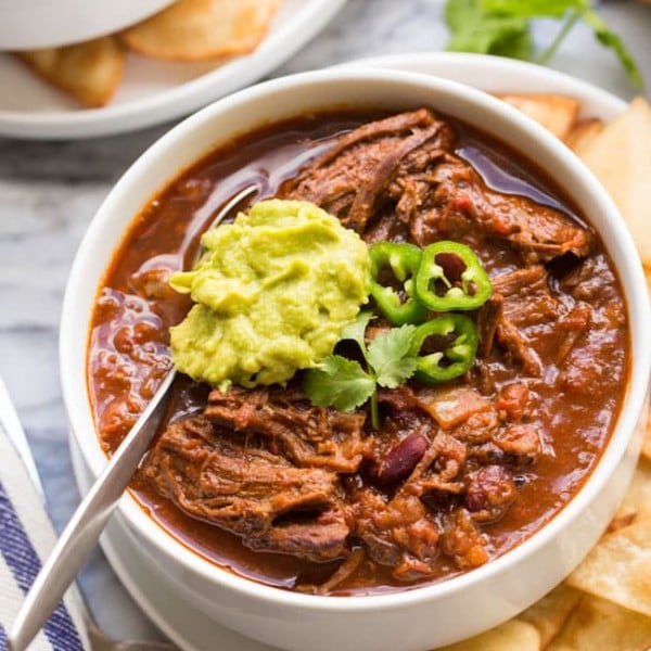 Instant-Pot-Chili-Con-Carne-with-Shredded-Beef in a white bowl topped with guacamole