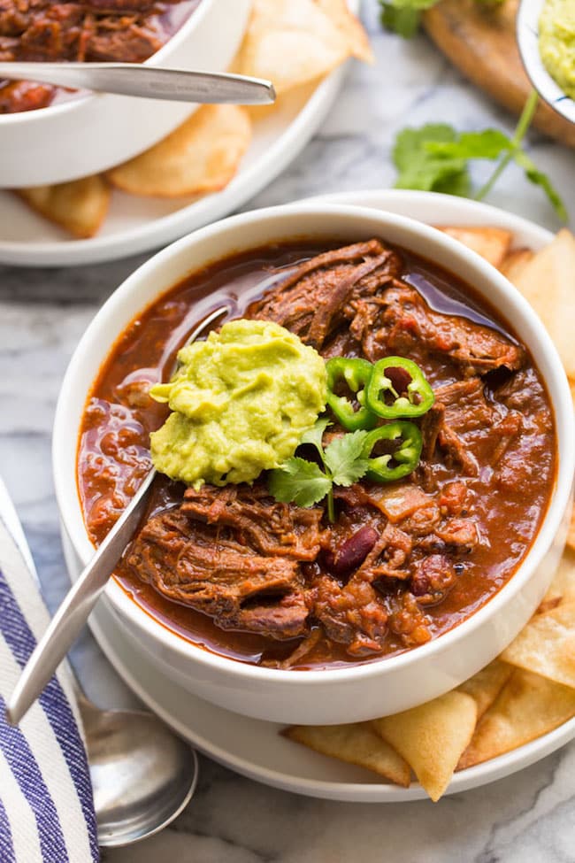 Instant Pot Chili Con Carne with Shredded Beef in a white bowl topped with guacamole