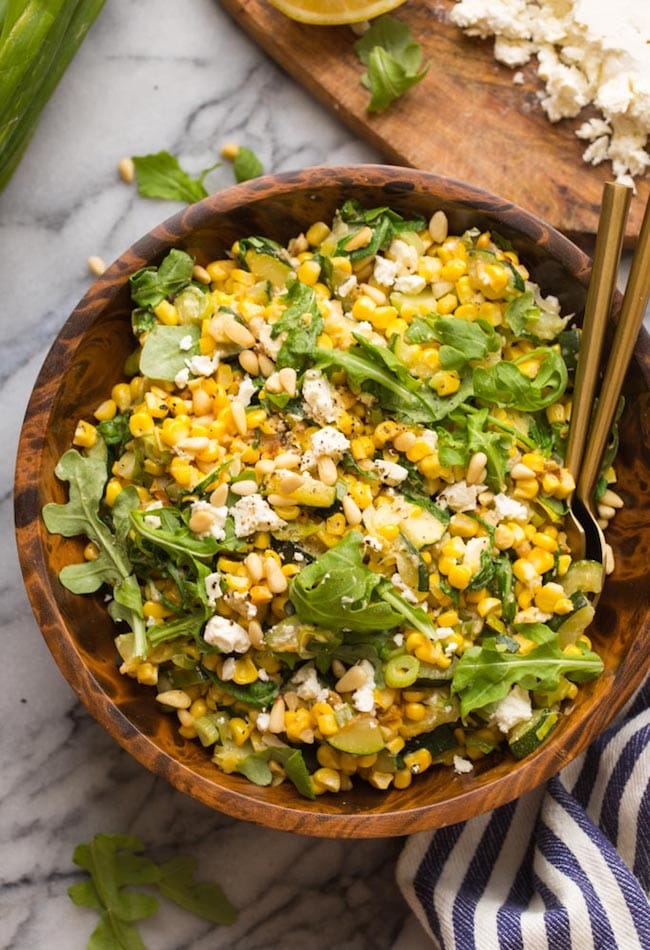 Sautéed Corn & Courgette Salad in a wooden bowl with golden spoons on the side