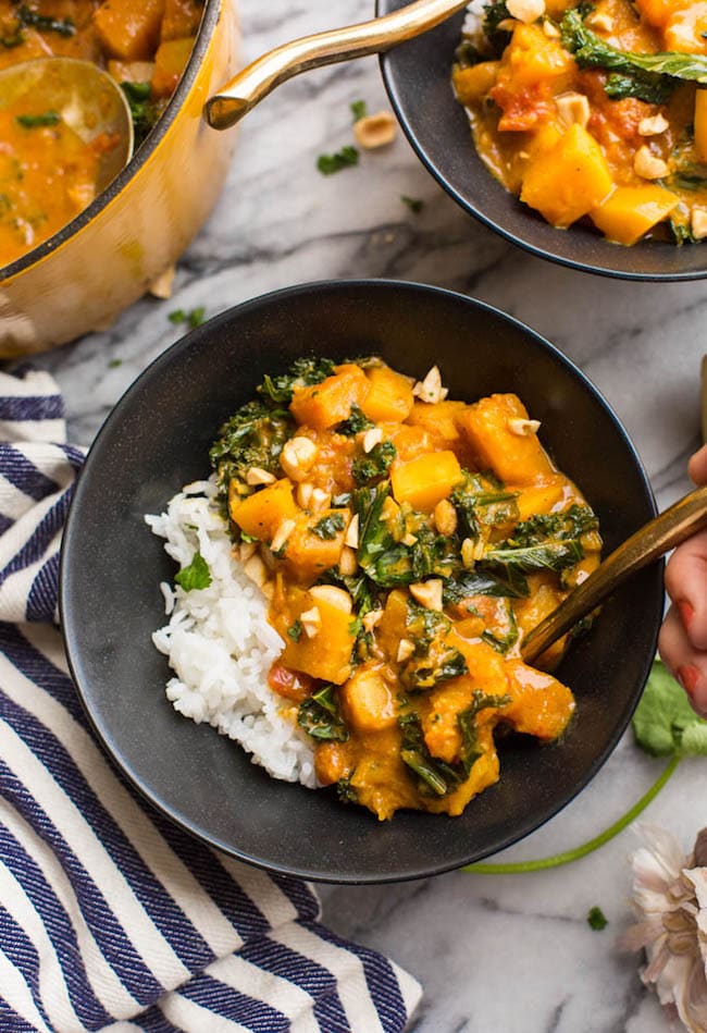 Peanut & Kale Butternut Squash Curry in a black serving bowl with a golden spoon