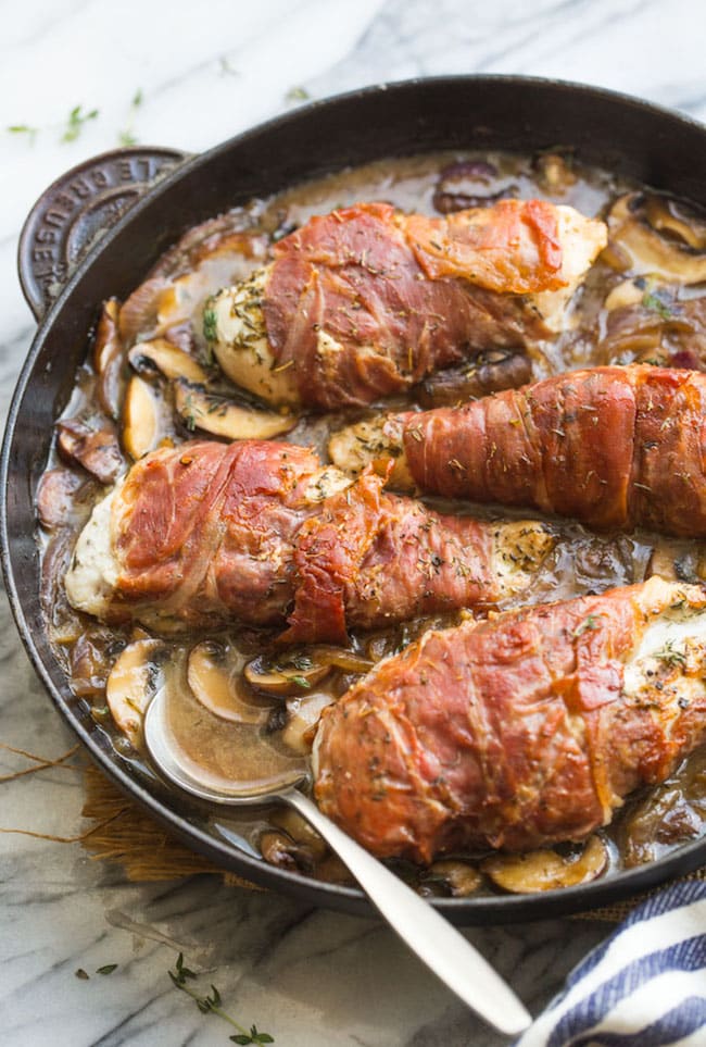 Prosciutto Wrapped Chicken with Mushrooms in a skillet with a spoon