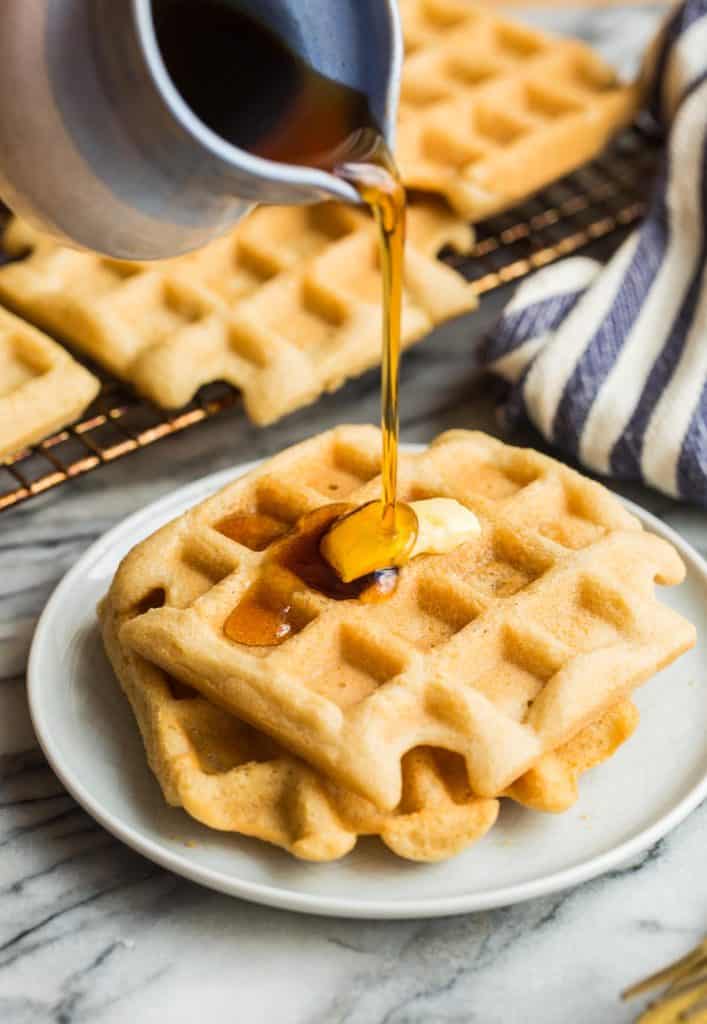 Almond Flour Waffles on a small plate with maple syrup pouring over the top