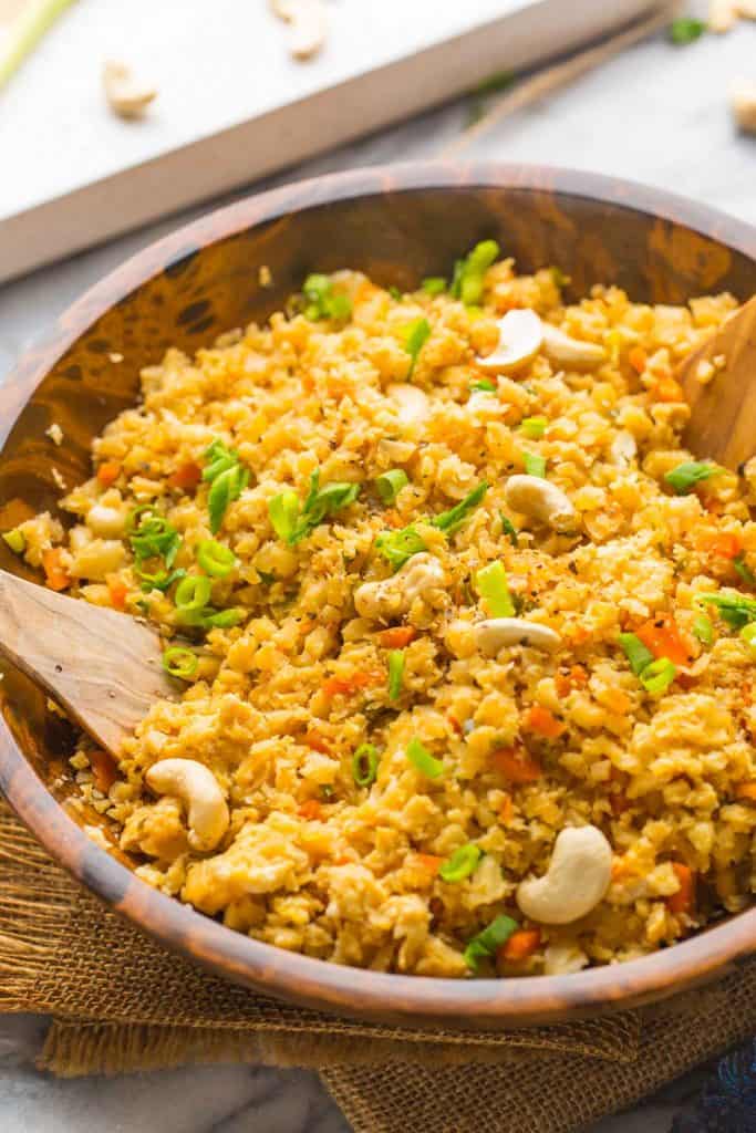 Cauliflower Egg Fried Rice topped with green onions in a wooden bowl