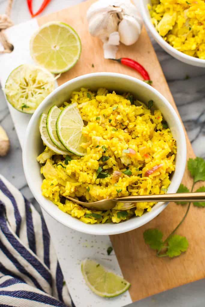 Instant Pot Coconut Lime Chicken and Rice in a bowl surrounded by limes, herbs and chilis