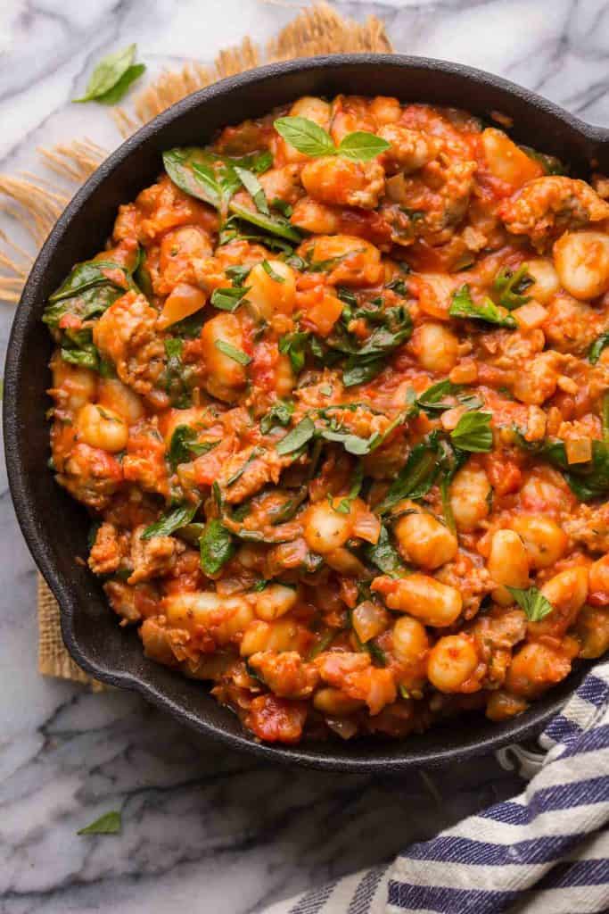 Fennel & Spinach Sausage Gnocchi in a cast iron skillet topped with basil