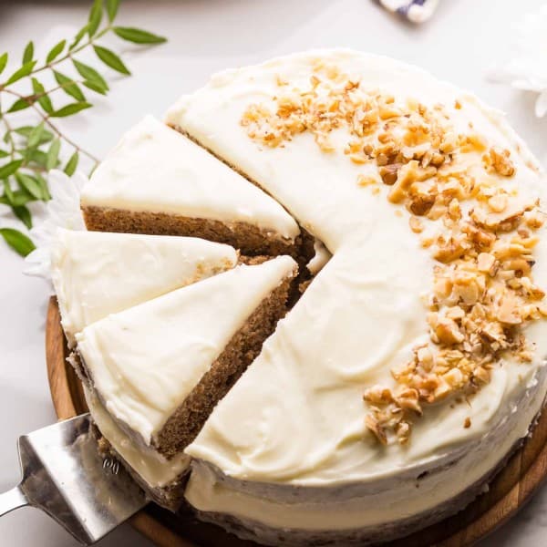 Gluten Free Carrot Cake topped with chopped walnuts on wooden platter