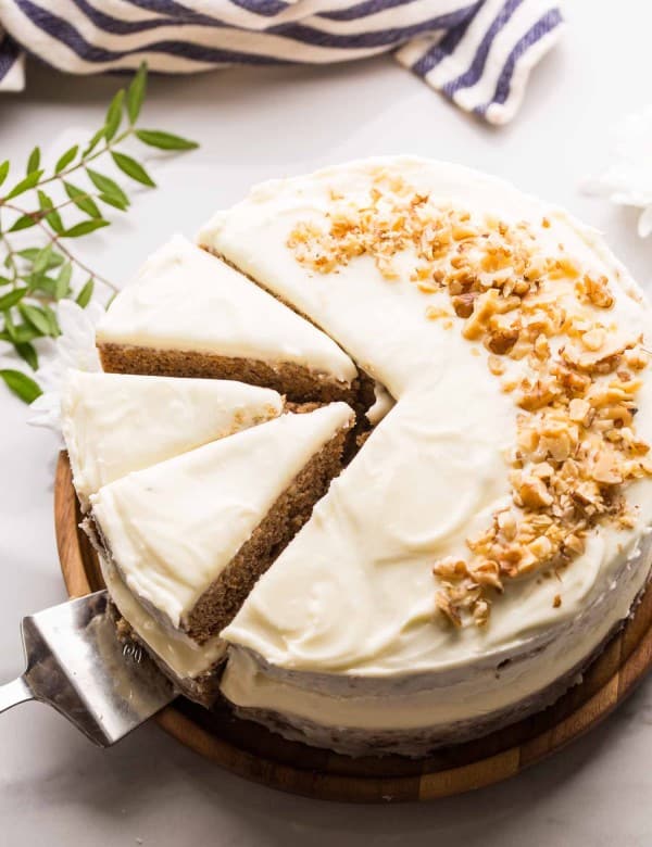 Gluten Free Carrot Cake topped with chopped walnuts on wooden platter