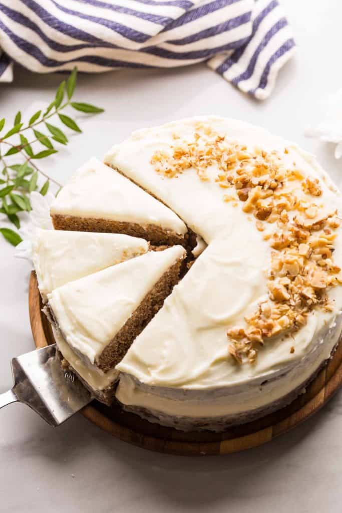 Gluten Free Carrot Cake topped with walnuts on a wooden platter