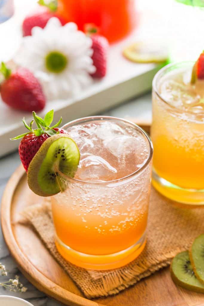 Strawberry Kiwi Gin & Tonic on a wooden plate garnished kiwi and strawberry