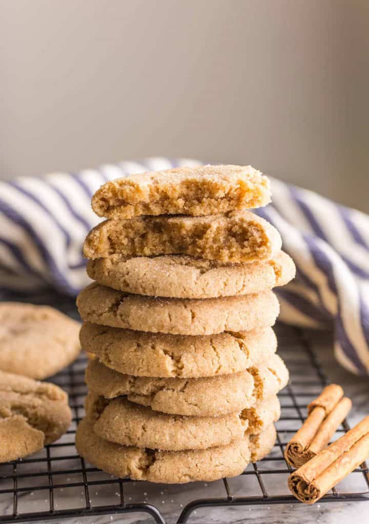 Almond Flour Snickerdoodles stacked on a wire cooling rack with one cookie cut in half