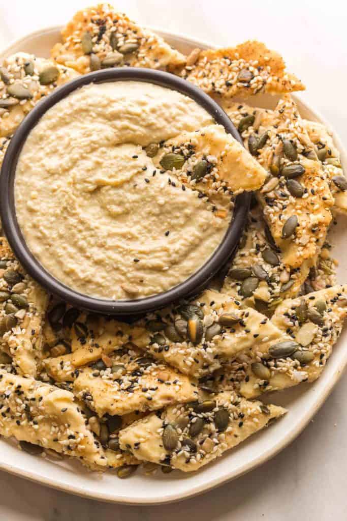 Seedy Everything Seasoned Crackers on a plate with hummus
