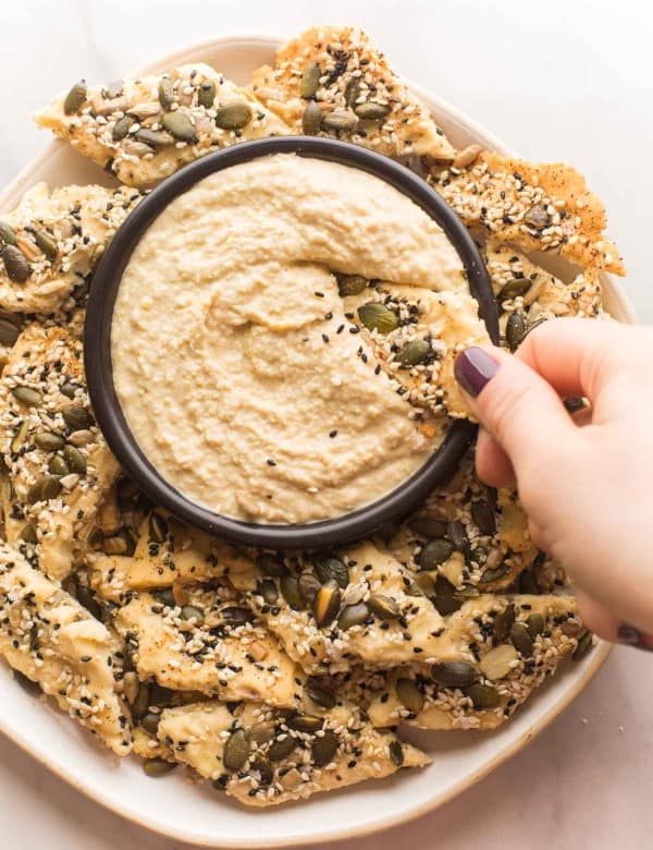 Everything-Seasoned-Crackers dipping into a bowl of hummus