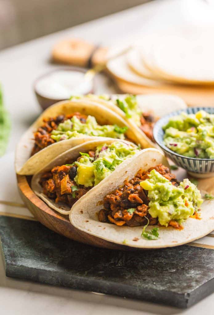 Vegan Black Bean Tacos & Mango Guacamole on a plate set on a marble slab