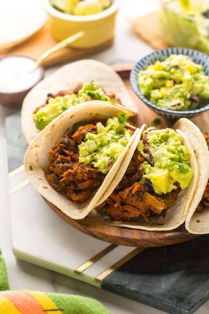 four Vegan Black Bean Tacos with Mango Guacamole on a plate