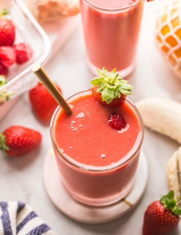 berry ginger smoothie on a coaster surrounded by fruit