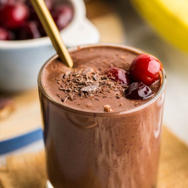 black forest smoothie in a small cup topped with cherries