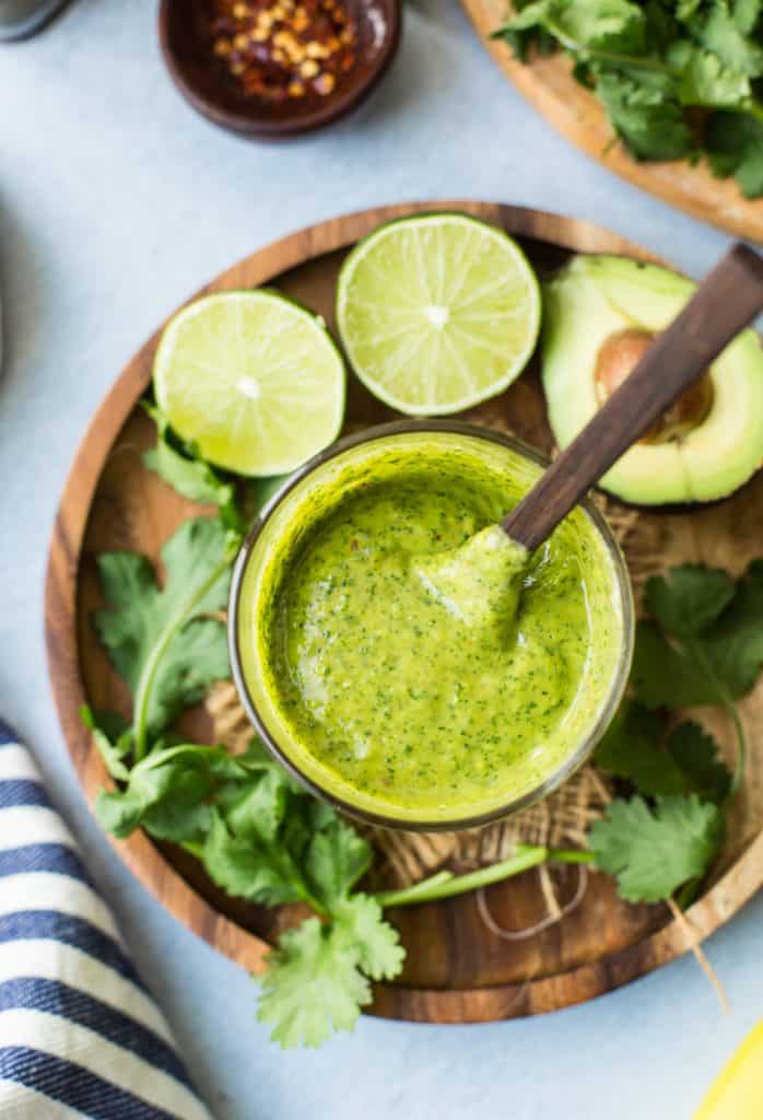 Cilantro Lime Dressing on a plate surrounded by avocado and lime