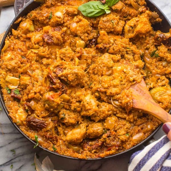 Italian-Quinoa-Sausage-Skillet topped with fresh herbs surrounded by ingredients