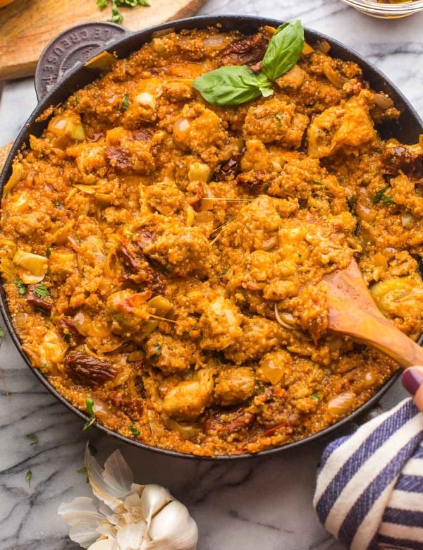 Italian-Quinoa-Sausage-Skillet topped with fresh herbs surrounded by ingredients