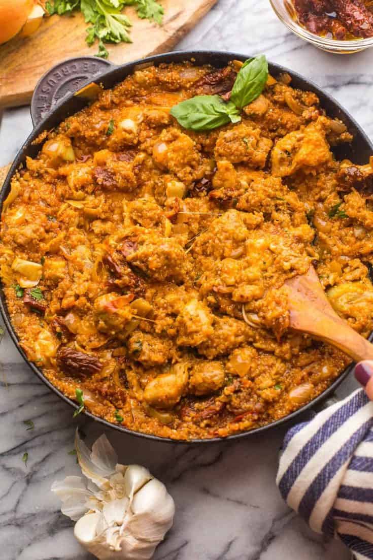 Italian-Quinoa-Sausage-Skillet topped with fresh herbs surrounded by ingredients