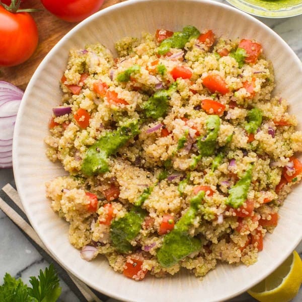 Tomato Quinoa Salad in a salad bowl surrounded by fresh veggies