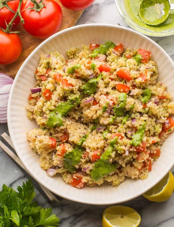 Tomato Quinoa Salad in a salad bowl surrounded by fresh veggies