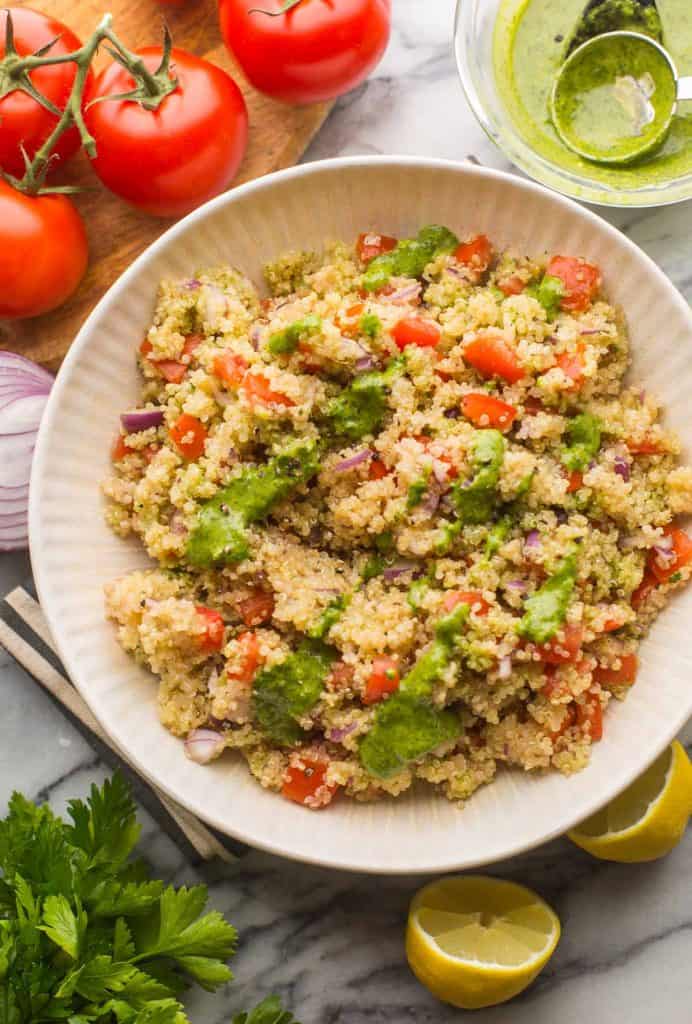 tomato quinoa salad in a bowl topped with zhoug dressing 