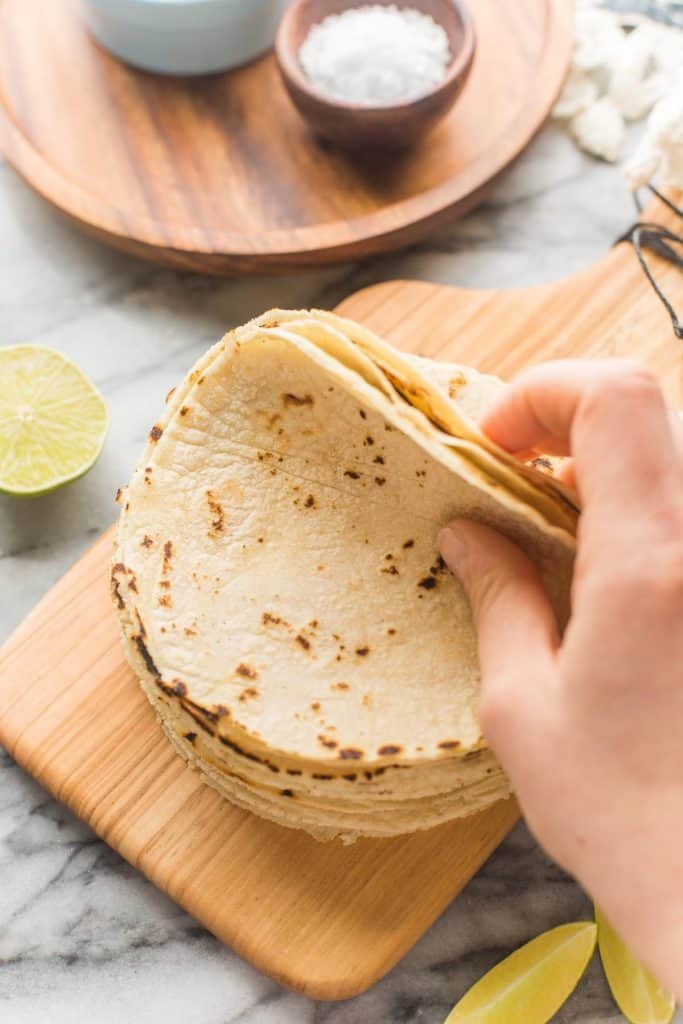 hand flipping back a stack of corn tortillas 