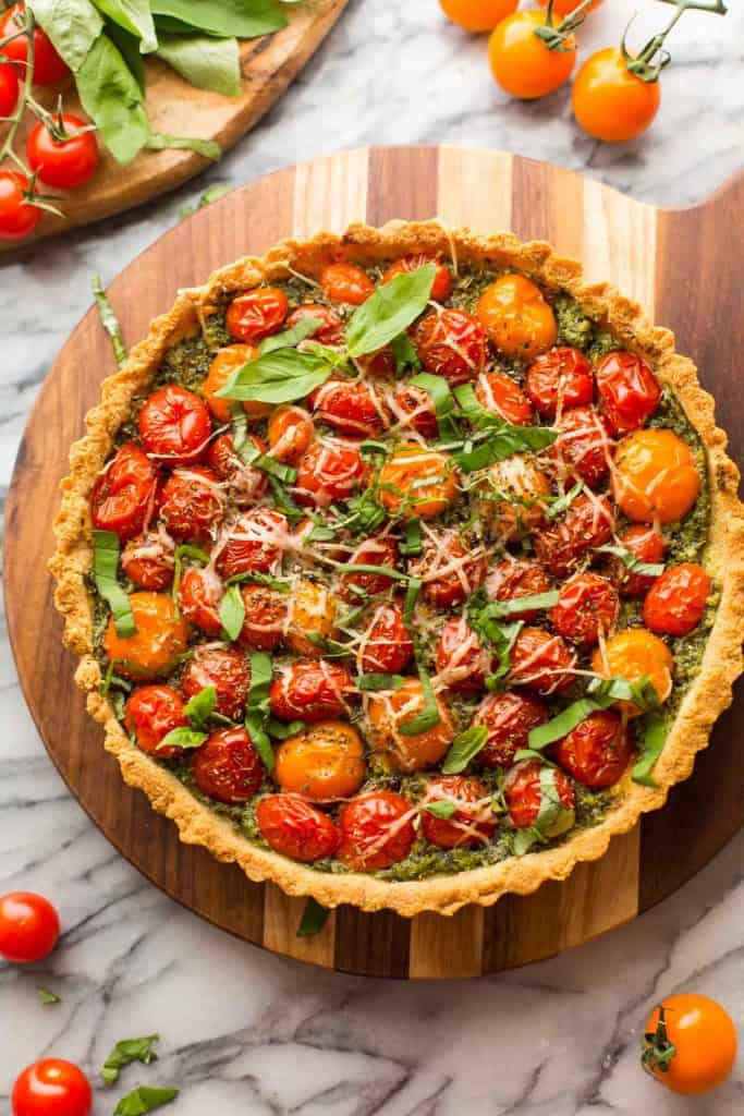 Almond Flour Tomato Tart topped with basil on a cutting board