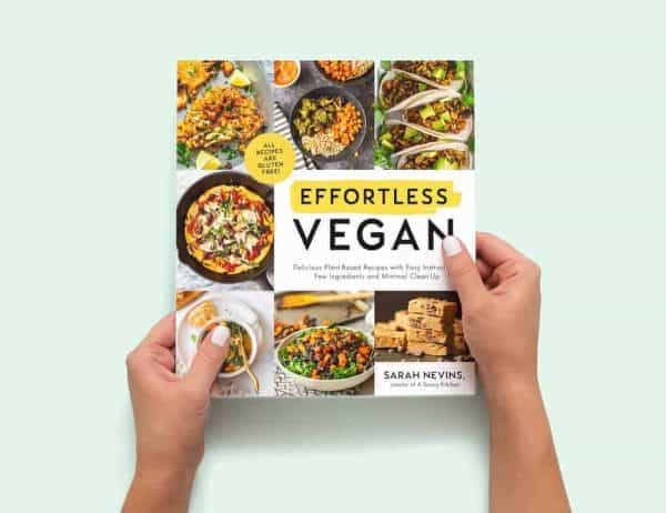 two hands holding a copy of the Effortless Vegan cookbook