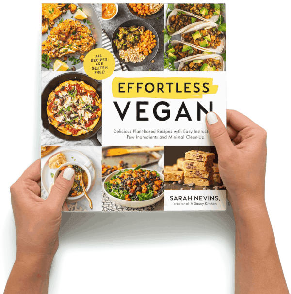 two hands holding a copy of the Effortless Vegan cookbook